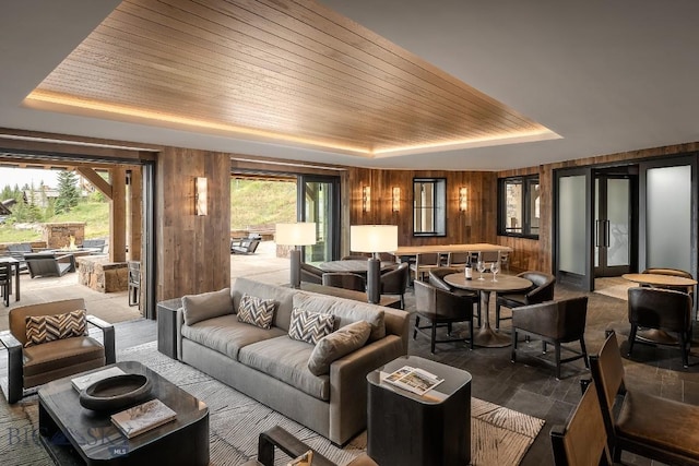 living room with plenty of natural light, wood walls, wooden ceiling, and a tray ceiling