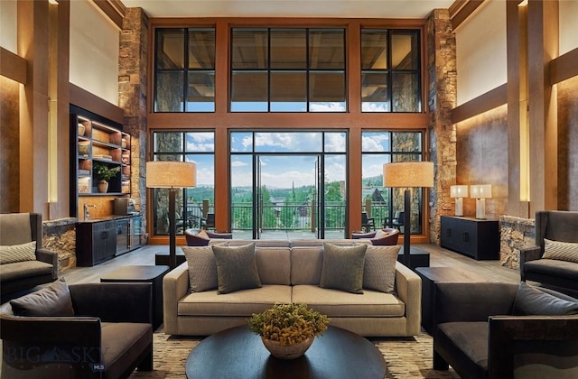 living area featuring built in shelves, wood finished floors, and a towering ceiling