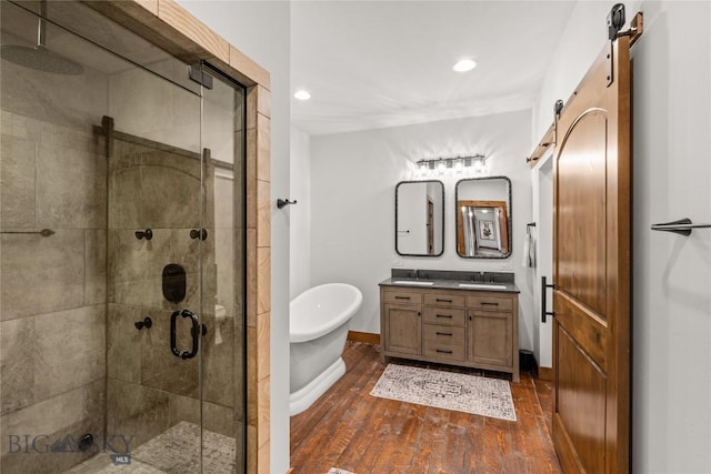 full bath with a stall shower, a sink, wood finished floors, double vanity, and a freestanding bath