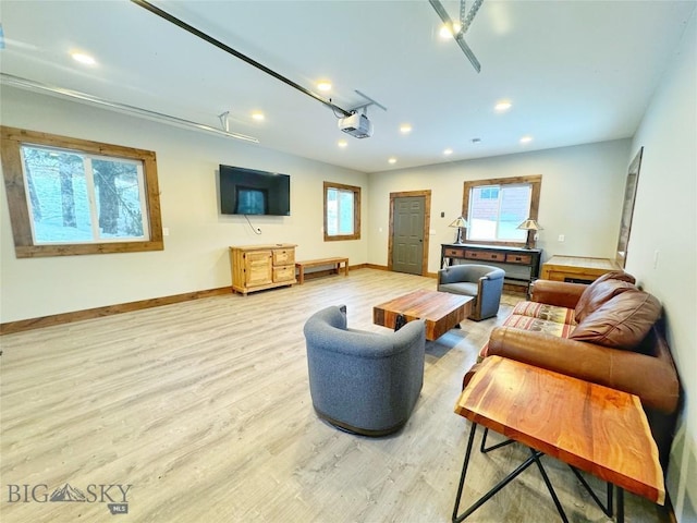 living room with recessed lighting, baseboards, a garage, and light wood finished floors