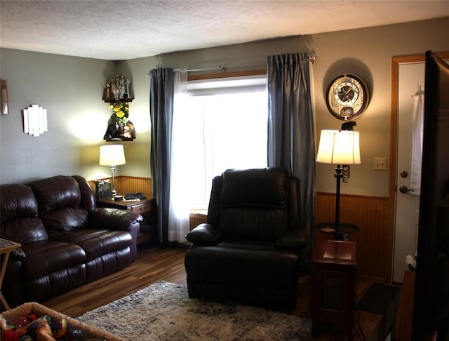 living room with a textured ceiling, wooden walls, wood finished floors, and wainscoting