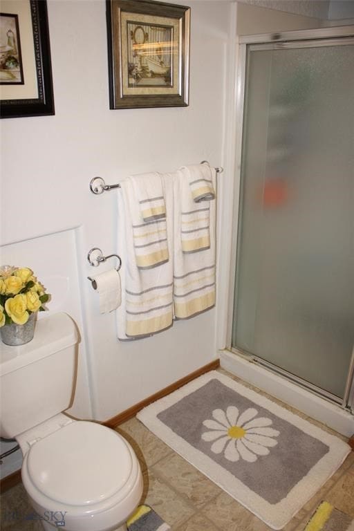 full bathroom featuring baseboards, toilet, and a shower stall