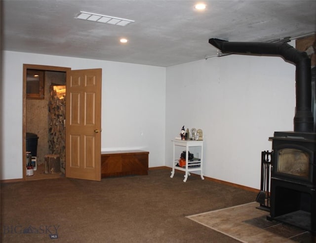 interior space with carpet, visible vents, baseboards, a wood stove, and recessed lighting