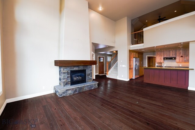 284 Annie Glade, Bozeman, MT 59718 - unfurnished living room featuring baseboards, dark wood-type flooring, ceiling fan, a fireplace, and stairway