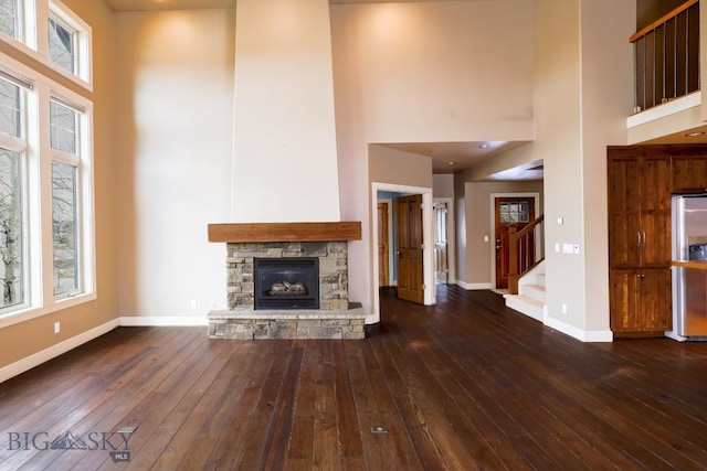 284 Annie Glade, Bozeman, MT 59718 - unfurnished living room with a towering ceiling, baseboards, dark wood-type flooring, a fireplace, and stairs