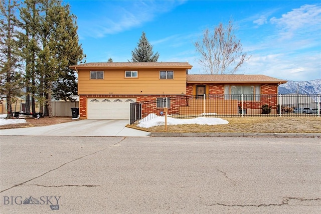 tri-level home featuring brick siding, an attached garage, concrete driveway, and fence