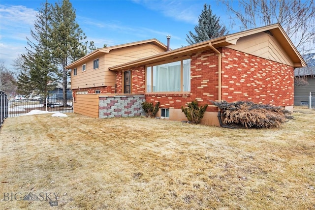 view of side of property with brick siding, a lawn, and fence