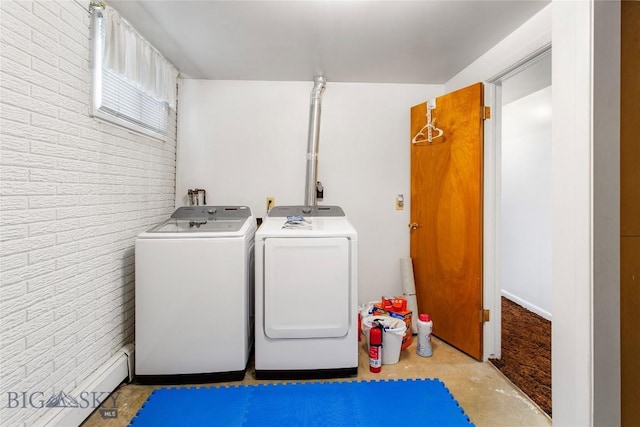 clothes washing area featuring laundry area, washing machine and dryer, and brick wall