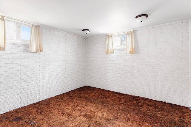 unfurnished room with brick wall and dark carpet