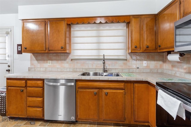 kitchen featuring a sink, stainless steel appliances, brown cabinets, and tasteful backsplash