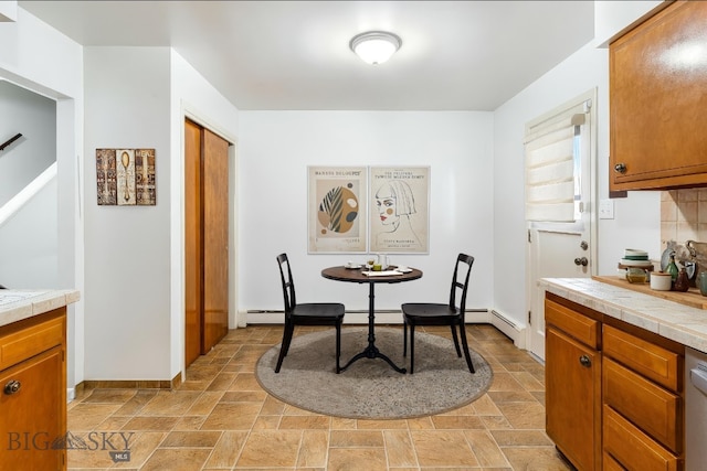 dining room featuring a baseboard heating unit, stone finish flooring, and baseboards