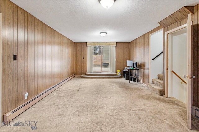 interior space featuring stairs, carpet flooring, wooden walls, a textured ceiling, and a baseboard radiator