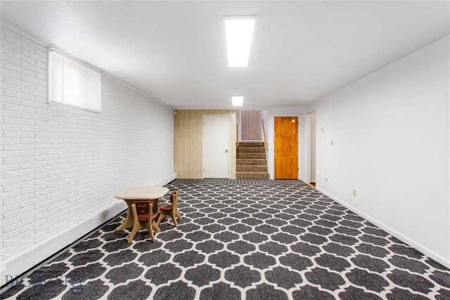 finished below grade area with baseboards, stairs, and brick wall
