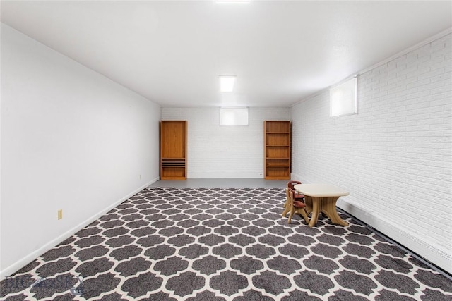 finished basement featuring baseboards and brick wall