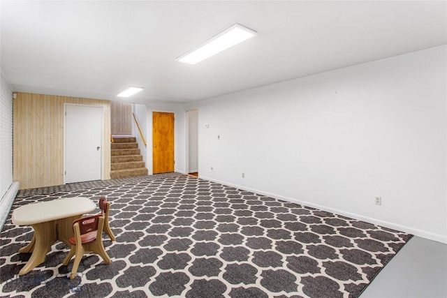 finished basement with wooden walls, baseboards, and stairway