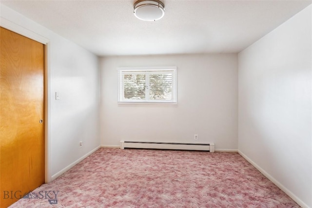 carpeted spare room featuring a baseboard heating unit and baseboards