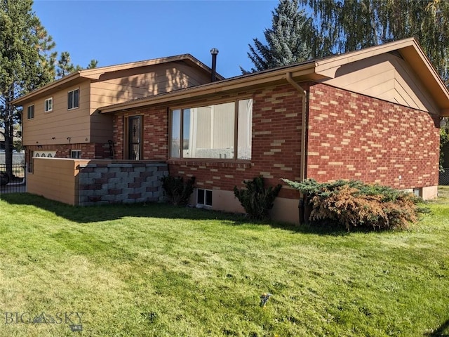 rear view of property featuring a lawn, fence, and brick siding