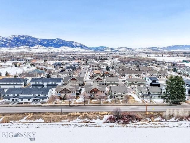 snowy aerial view featuring a mountain view and a residential view