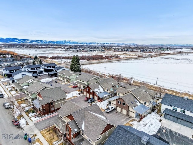 snowy aerial view featuring a mountain view and a residential view