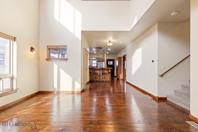 foyer featuring baseboards, wood-type flooring, a healthy amount of sunlight, and stairway