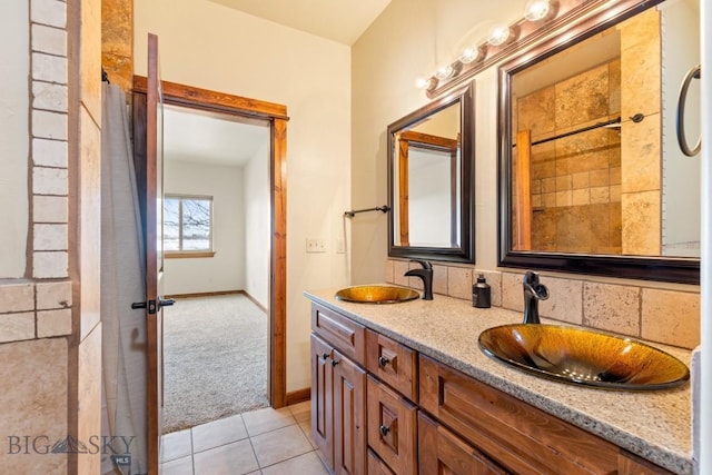 full bath with tile patterned flooring, double vanity, baseboards, and a sink