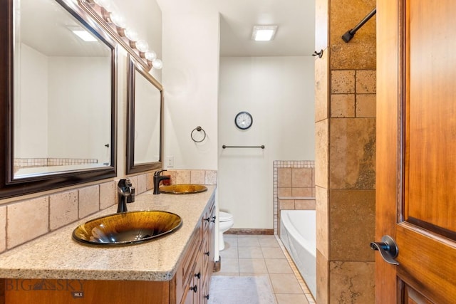 bathroom featuring a bathtub, double vanity, toilet, and a sink