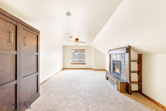 additional living space with light colored carpet, a large fireplace, baseboards, and vaulted ceiling