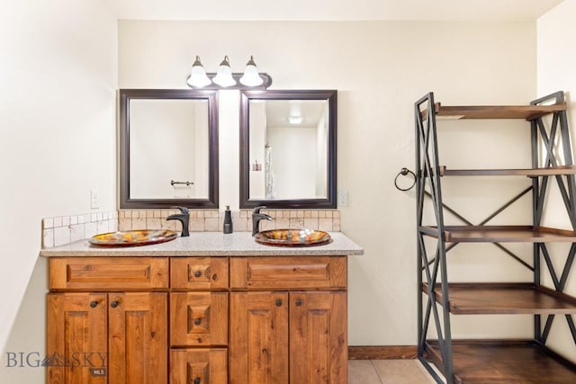 bathroom with tasteful backsplash, tile patterned flooring, double vanity, and a sink