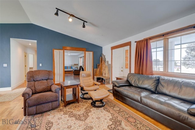 living room with baseboards, rail lighting, and vaulted ceiling