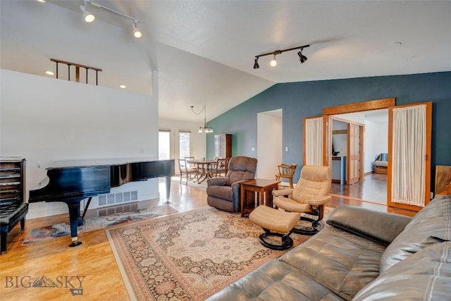 living room featuring wood finished floors, track lighting, and vaulted ceiling