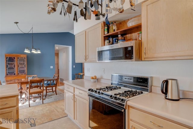 kitchen featuring lofted ceiling, light countertops, gas range oven, stainless steel microwave, and a chandelier