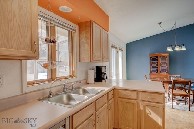 kitchen with a chandelier, light brown cabinets, a peninsula, and a sink