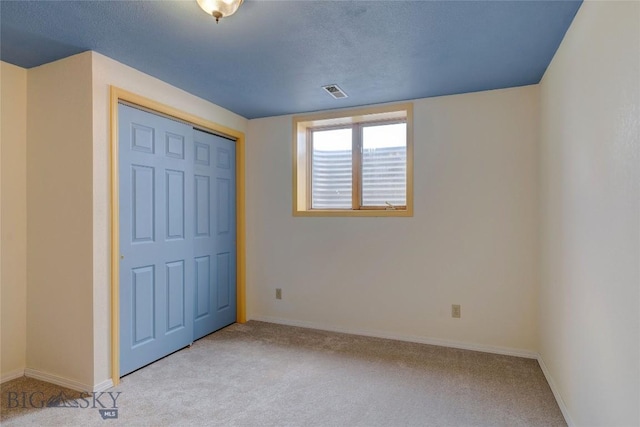 unfurnished bedroom with visible vents, a textured ceiling, a closet, carpet floors, and baseboards