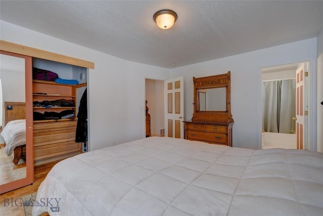 bedroom with a closet, ensuite bathroom, and a textured ceiling