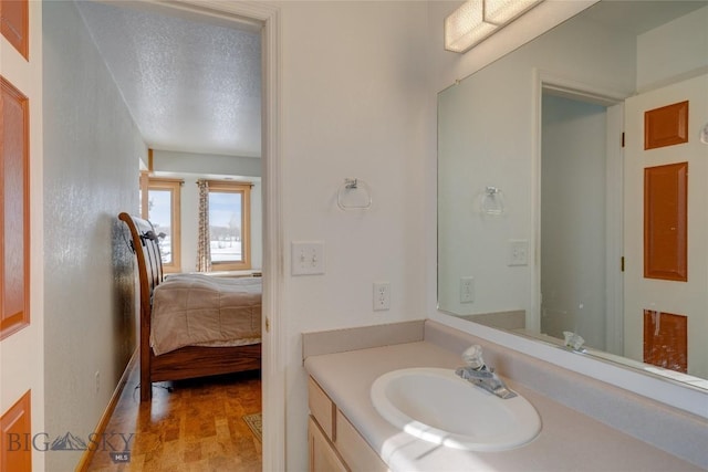 bathroom with vanity, wood finished floors, baseboards, ensuite bath, and a textured ceiling