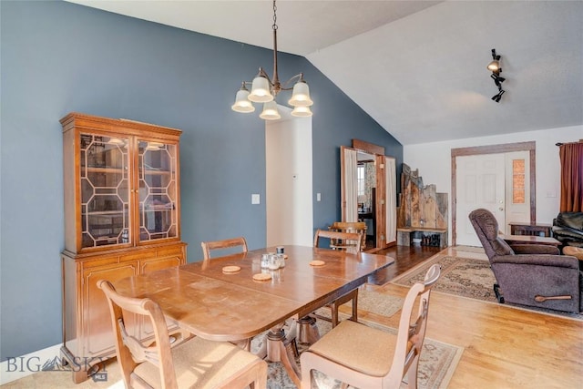 dining space featuring a notable chandelier, lofted ceiling, and wood finished floors