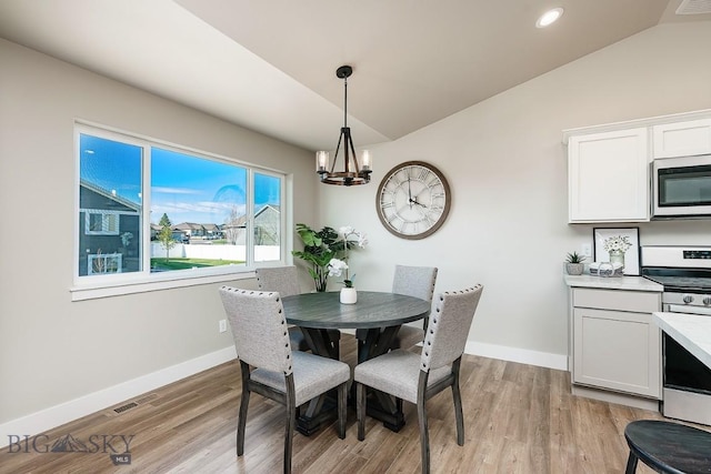 dining room with a notable chandelier, baseboards, light wood-type flooring, and lofted ceiling