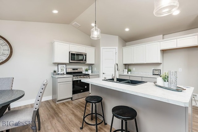 kitchen with visible vents, a breakfast bar, a sink, appliances with stainless steel finishes, and light countertops