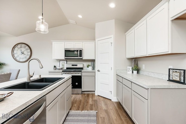 kitchen featuring light countertops, vaulted ceiling, light wood-style floors, stainless steel appliances, and a sink