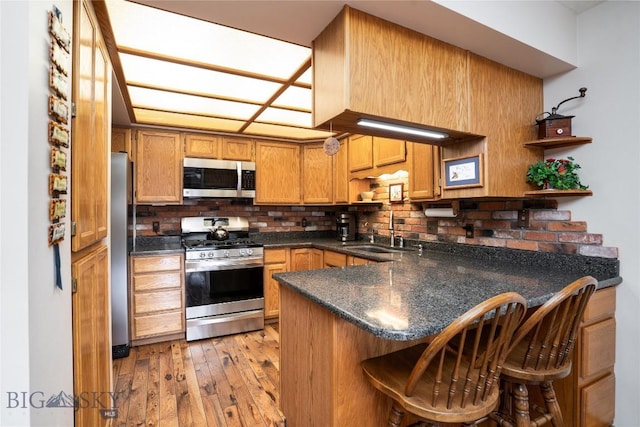 kitchen with open shelves, light wood-style flooring, a peninsula, a sink, and stainless steel appliances