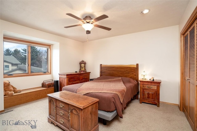 bedroom featuring a ceiling fan, visible vents, baseboards, a closet, and light colored carpet