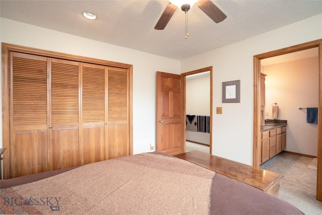 bedroom featuring a closet, light carpet, ensuite bathroom, and a ceiling fan