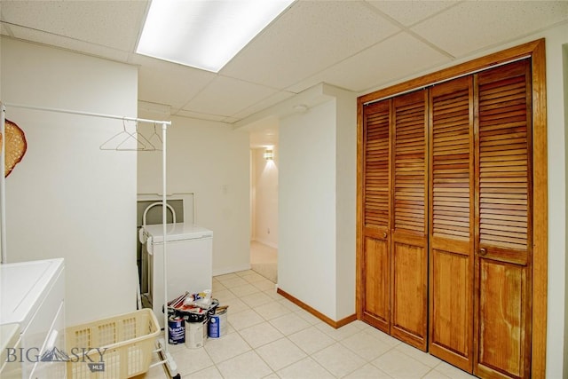 washroom featuring laundry area, light tile patterned flooring, washing machine and dryer, and baseboards