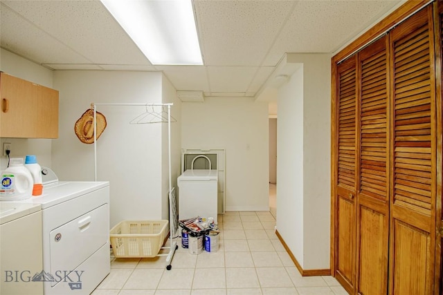 laundry room with light tile patterned floors, washer and dryer, cabinet space, and baseboards