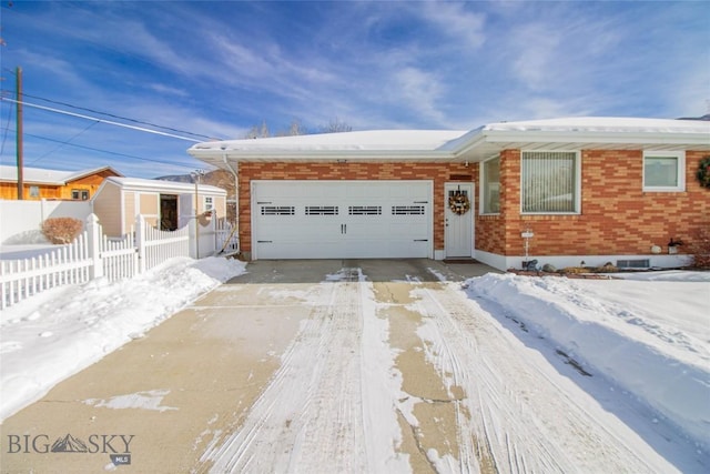 view of front of home with a garage, brick siding, concrete driveway, and fence