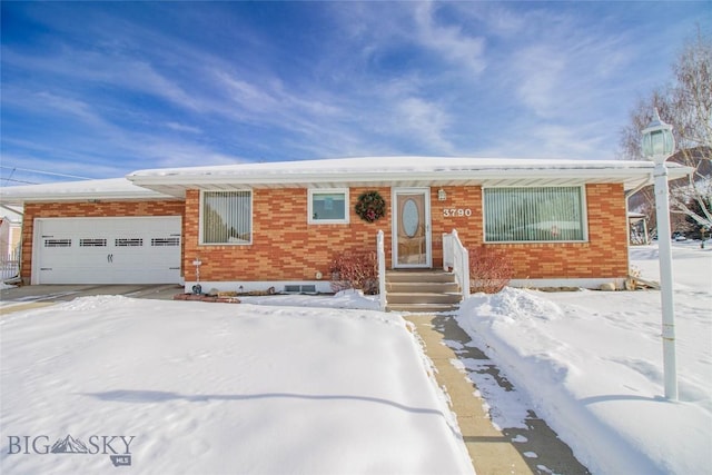 single story home with brick siding, a garage, and driveway