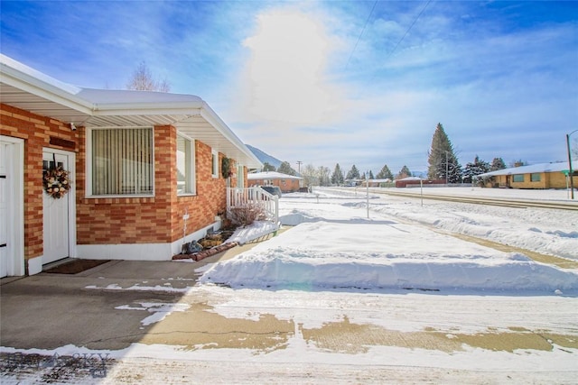 view of snow covered exterior featuring brick siding