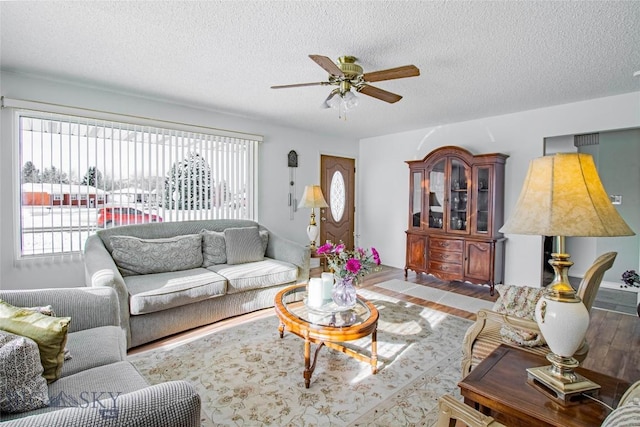 living room with ceiling fan, a textured ceiling, and wood finished floors