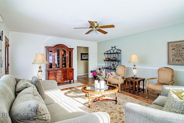 living area featuring baseboards, wood finished floors, and a ceiling fan