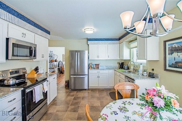 kitchen featuring light stone countertops, white cabinetry, stainless steel appliances, and a sink